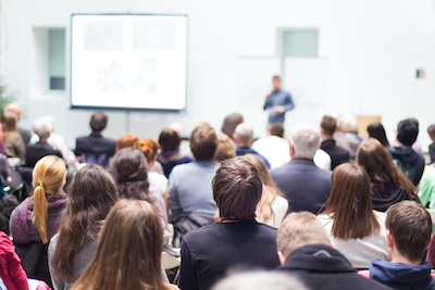 Een grote groep mensen bij een presentatie van GGZ Ecademy | Onze missie